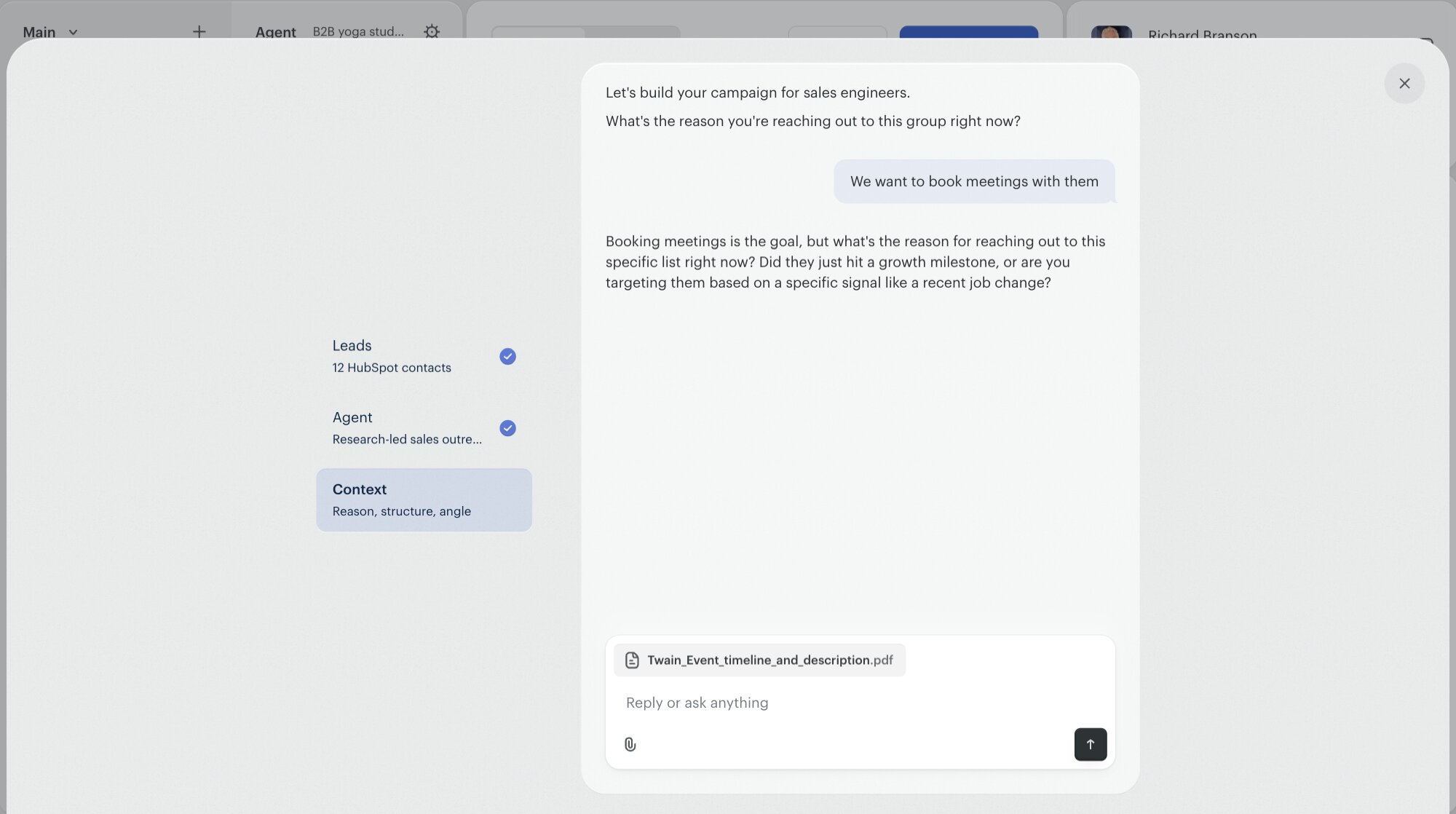 The Twain Campaign Brief chat. Leads (12 HubSpot contacts) and Agent (Research-led sales outreach) are checked on the left rail; Context is the active step. The assistant says 'Let's build your campaign for sales engineers. What's the reason you're reaching out to this group right now?' The user replies 'We want to book meetings with them.' The assistant probes: 'Booking meetings is the goal, but what's the reason for reaching out to this specific list right now?' A PDF (Twain_Event_timeline_and_description.pdf) is attached in the composer.